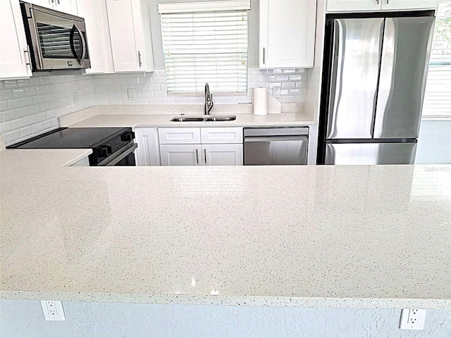 450 82nd Ave, St Pete Beach, FL 33706 - kitchen featuring appliances with stainless steel finishes, backsplash, and white cabinets