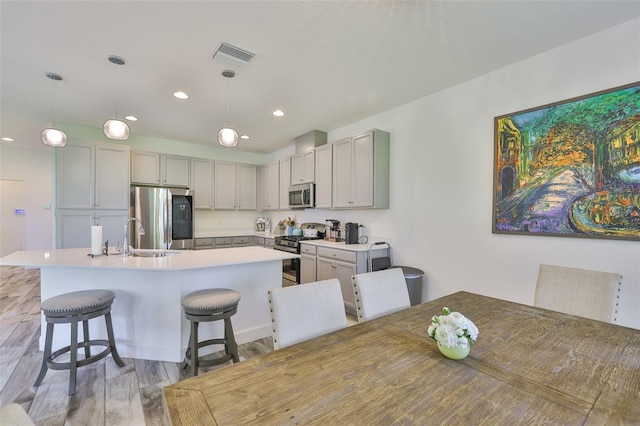 6215 Voyagers Pl, Apollo Beach, FL 33572 - kitchen with appliances with stainless steel finishes, a kitchen breakfast bar, light wood-type flooring, light countertops, and a kitchen island with sink