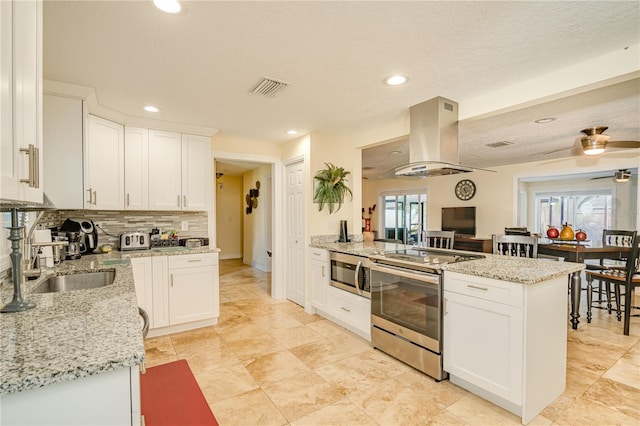 1954 Arvis Cir W, Clearwater, FL 33764 - kitchen featuring appliances with stainless steel finishes, island exhaust hood, a peninsula, decorative backsplash, and white cabinetry