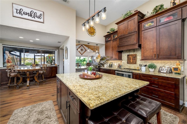 3539 Lake Padgett Dr, Land O Lakes, FL 34639 - kitchen featuring wood finished floors, light stone counters, decorative backsplash, a kitchen island, and a towering ceiling
