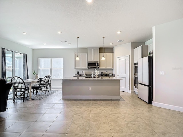 35428 Crescent Creek Dr, Zephyrhills, FL 33541 - kitchen featuring stainless steel appliances, a kitchen island with sink, recessed lighting, light tile patterned floors, and light stone counters