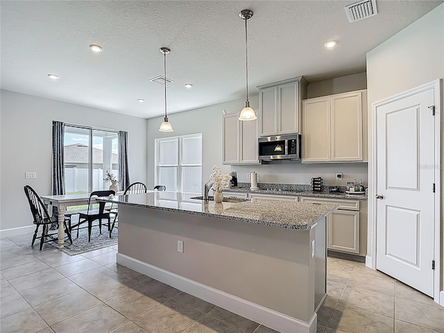 35428 Crescent Creek Dr, Zephyrhills, FL 33541 - kitchen with appliances with stainless steel finishes, light stone counters, a center island with sink, recessed lighting, and light tile patterned floors