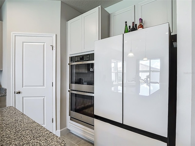 35428 Crescent Creek Dr, Zephyrhills, FL 33541 - kitchen with double oven, freestanding refrigerator, white cabinets, light tile patterned floors, and dark stone countertops