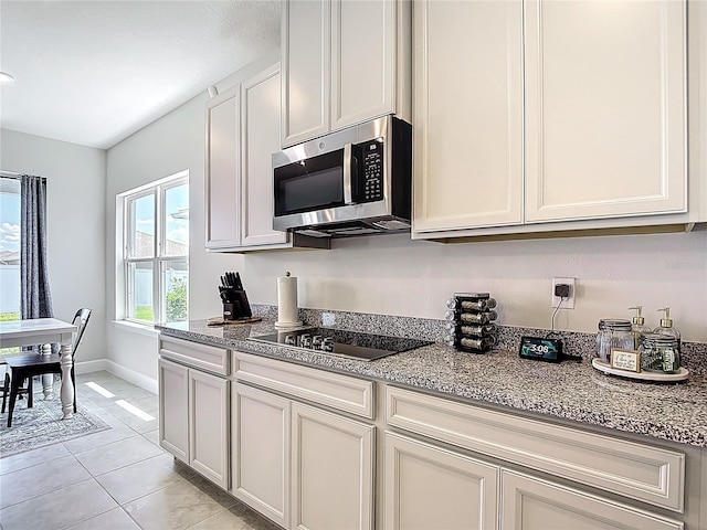35428 Crescent Creek Dr, Zephyrhills, FL 33541 - kitchen with stainless steel microwave, black electric stovetop, light tile patterned floors, and light stone counters