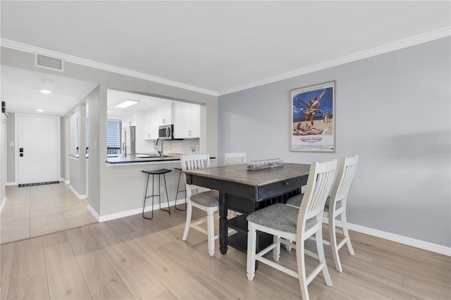 9495 Blind Pass Rd Unit 1103, St Pete Beach, FL 33706 - dining room featuring light wood-type flooring and crown molding