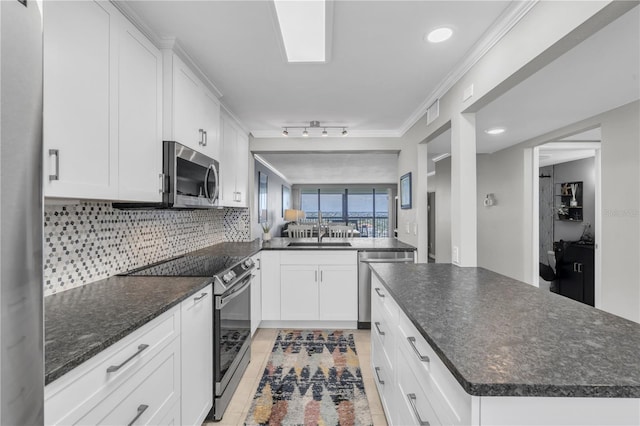 9495 Blind Pass Rd Unit 1103, St Pete Beach, FL 33706 - kitchen with stainless steel appliances, backsplash, white cabinets, a kitchen island, and crown molding