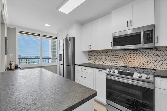 9495 Blind Pass Rd Unit 1103, St Pete Beach, FL 33706 - kitchen featuring appliances with stainless steel finishes, dark countertops, white cabinets, backsplash, and recessed lighting