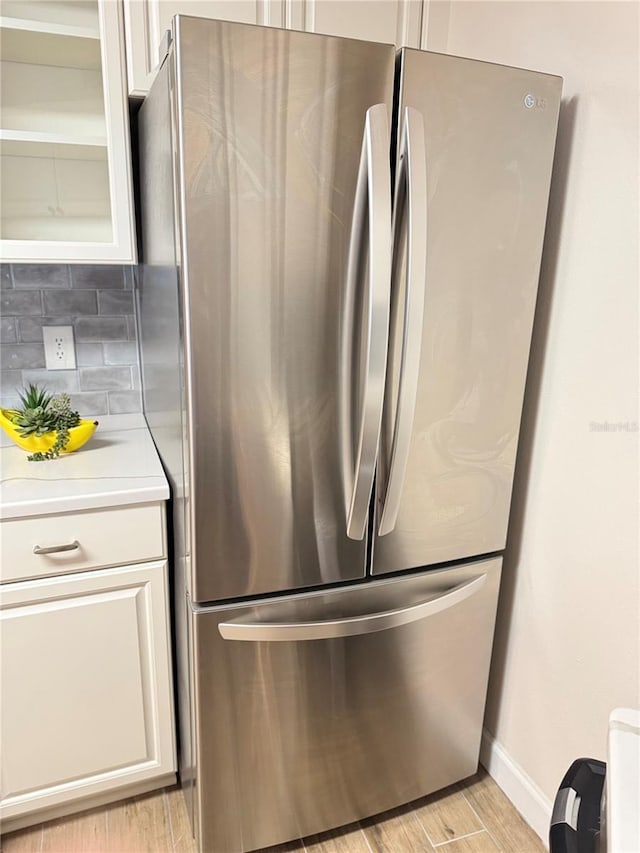 1550 S Belcher Rd Unit 335, Clearwater, FL 33764 - kitchen with freestanding refrigerator, light countertops, tasteful backsplash, light wood-type flooring, and white cabinetry