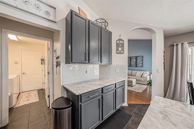 3509 Williston Loop, Land O Lakes, FL 34639 - kitchen featuring backsplash, arched walkways, a textured ceiling, light stone countertops, and dark tile patterned floors