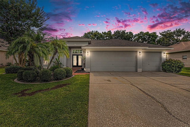 3509 Williston Loop, Land O Lakes, FL 34639 - view of front of property with stucco siding, concrete driveway, an attached garage, a yard, and french doors