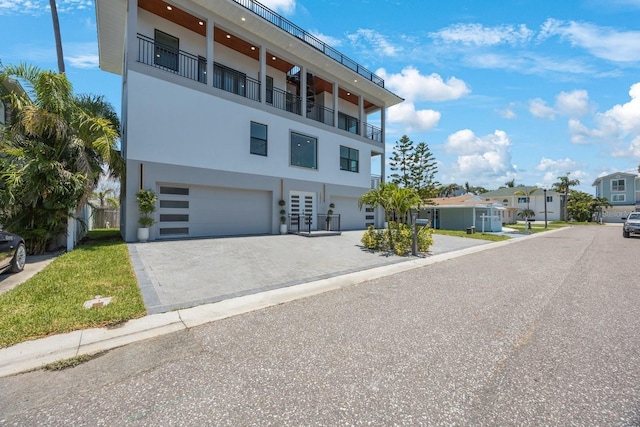 18077 3rd St E, Redington Shores, FL 33708 - view of front of house with stucco siding, decorative driveway, a garage, and a residential view