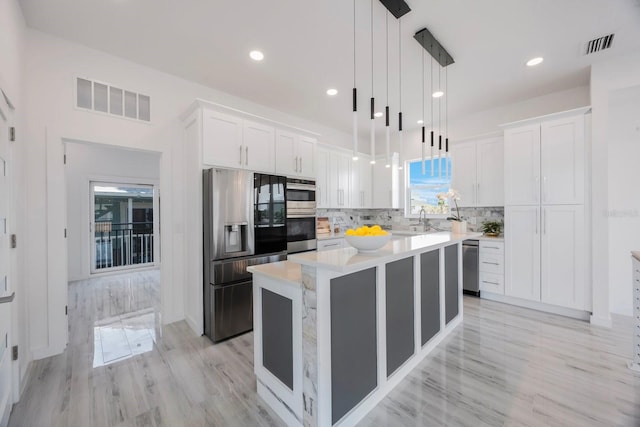 18077 3rd St E, Redington Shores, FL 33708 - kitchen featuring stainless steel fridge with ice dispenser, light countertops, white cabinetry, a center island, and recessed lighting