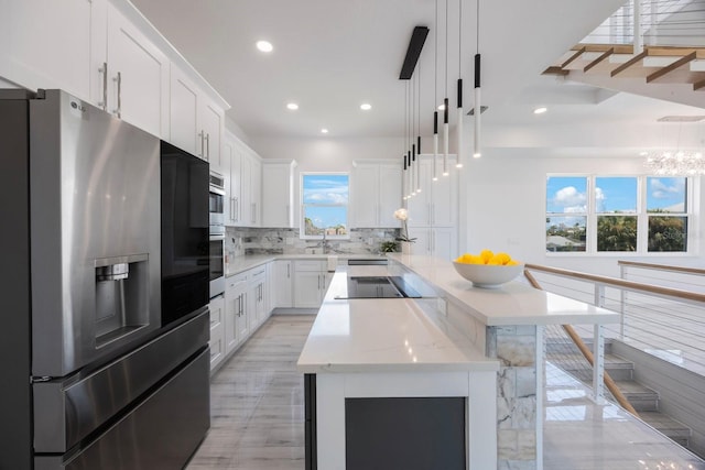 18077 3rd St E, Redington Shores, FL 33708 - kitchen with stainless steel fridge with ice dispenser, black electric stovetop, backsplash, a center island, and white cabinetry