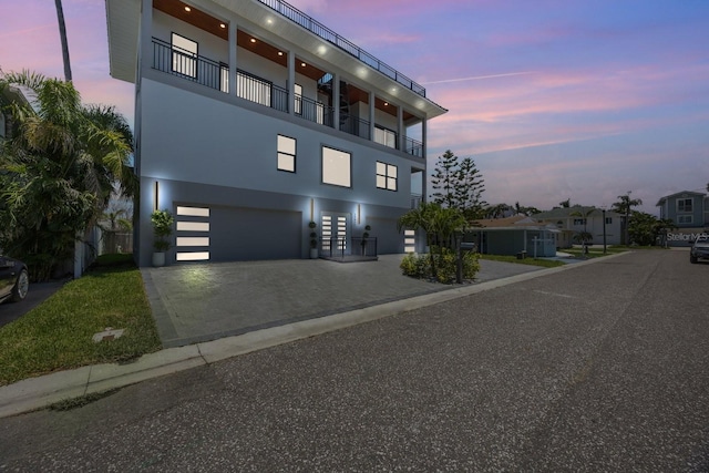 18077 3rd St E, Redington Shores, FL 33708 - view of front of property featuring stucco siding, an attached garage, decorative driveway, and a balcony