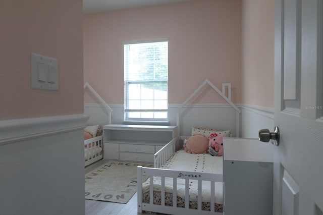 2522 W Castle Rd, Dunnellon, FL 34434 - bedroom featuring a crib, wood finished floors, and wainscoting