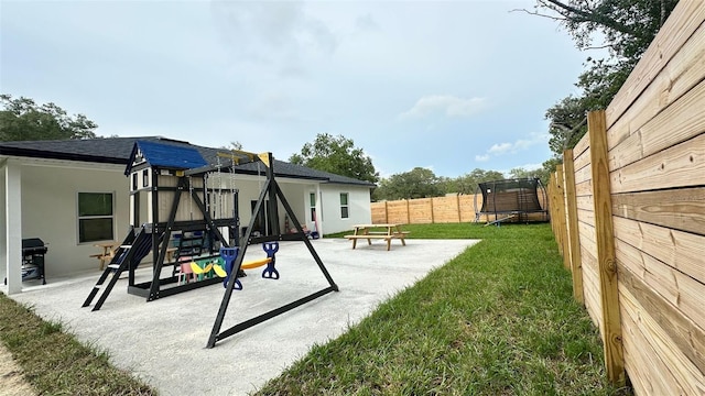 2522 W Castle Rd, Dunnellon, FL 34434 - fenced backyard featuring a trampoline, a playground, and a patio area