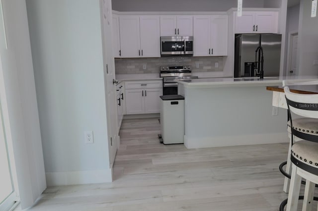 2522 W Castle Rd, Dunnellon, FL 34434 - kitchen with stainless steel appliances, light wood finished floors, backsplash, and white cabinets
