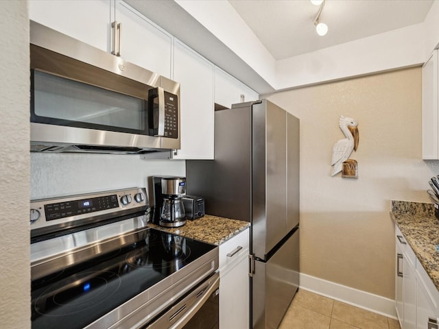 10265 Gulf Blvd Unit A107, Saint Petersburg, FL 33706 - kitchen with appliances with stainless steel finishes, white cabinets, light stone countertops, and light tile patterned floors