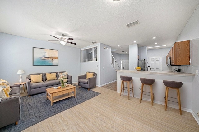 8118 Stone Path Way, Tampa, FL 33647 - living area with a ceiling fan, light wood-style flooring, stairway, a textured ceiling, and recessed lighting