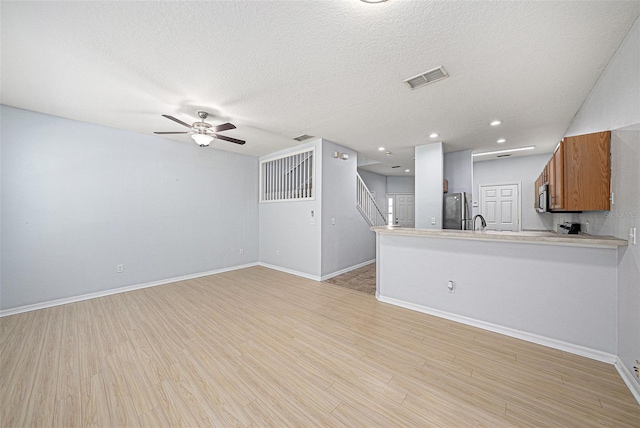 8118 Stone Path Way, Tampa, FL 33647 - unfurnished living room featuring ceiling fan, light wood-type flooring, a textured ceiling, stairway, and recessed lighting