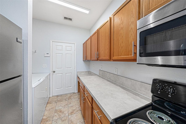 8118 Stone Path Way, Tampa, FL 33647 - kitchen featuring appliances with stainless steel finishes, brown cabinets, light countertops, and washing machine and dryer