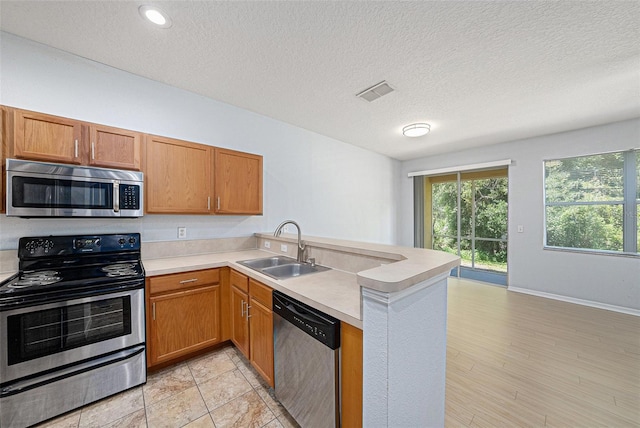 8118 Stone Path Way, Tampa, FL 33647 - kitchen with appliances with stainless steel finishes, a peninsula, light countertops, a textured ceiling, and brown cabinets