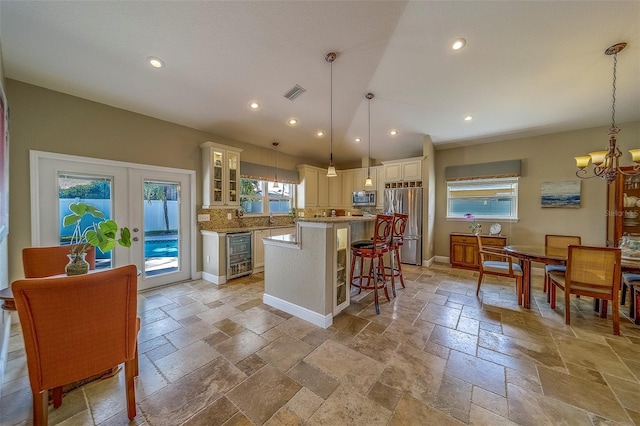 13425 San Rafael Dr, Largo, FL 33774 - kitchen with wine cooler, appliances with stainless steel finishes, stone tile floors, a chandelier, and a kitchen breakfast bar