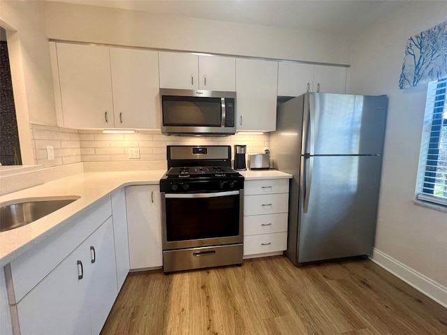 1359 Mission Cir Unit 48A, Clearwater, FL 33759 - kitchen featuring appliances with stainless steel finishes, light wood finished floors, decorative backsplash, and white cabinetry
