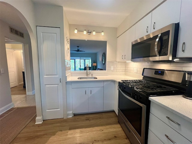 1359 Mission Cir Unit 48A, Clearwater, FL 33759 - kitchen featuring stainless steel appliances, arched walkways, white cabinetry, decorative backsplash, and wood finished floors