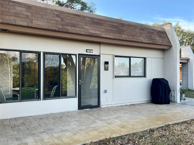 1359 Mission Cir Unit 48A, Clearwater, FL 33759 - back of property with a shingled roof, a patio area, and mansard roof