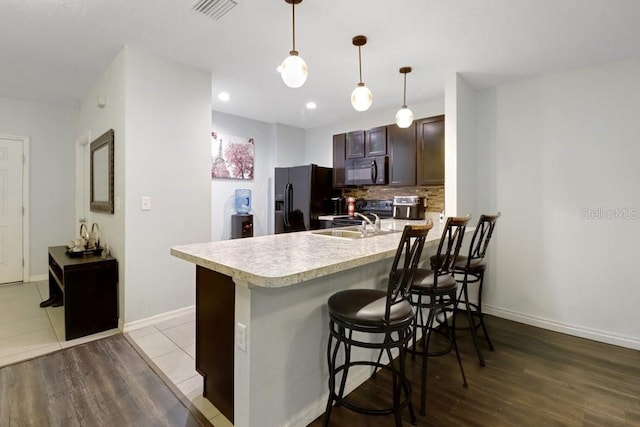9826 Hound Chase Dr, Gibsonton, FL 33534 - kitchen with black appliances, light countertops, a peninsula, dark brown cabinets, and backsplash