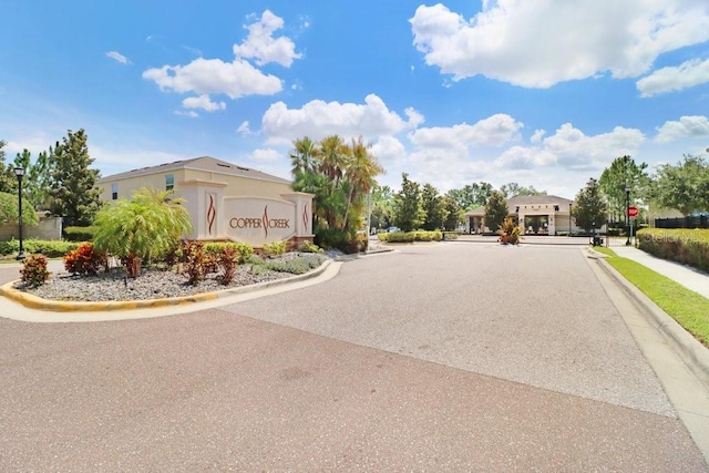 9826 Hound Chase Dr, Gibsonton, FL 33534 - view of asphalt road with curbs, sidewalks, traffic signs, street lights, and a gated entry