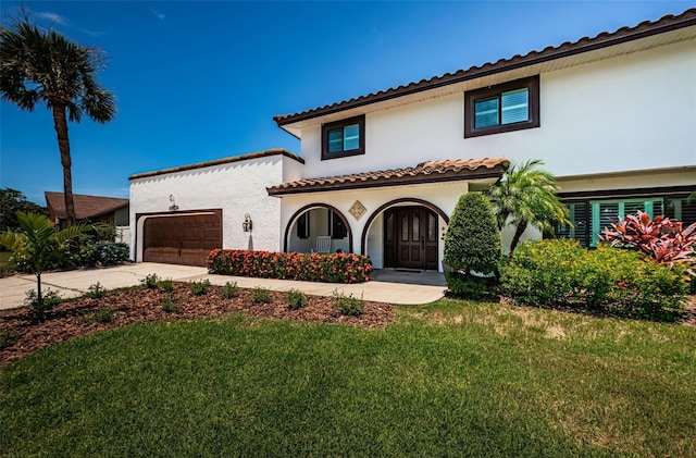 10866 Harborside Dr, Largo, FL 33773 - mediterranean / spanish-style home featuring stucco siding, driveway, a front lawn, an attached garage, and a porch