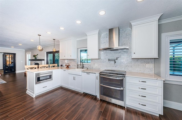 10866 Harborside Dr, Largo, FL 33773 - kitchen featuring a peninsula, range with two ovens, wall chimney exhaust hood, tasteful backsplash, and white cabinetry