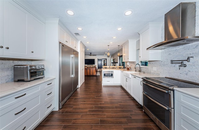 10866 Harborside Dr, Largo, FL 33773 - kitchen with appliances with stainless steel finishes, wall chimney range hood, a peninsula, recessed lighting, and white cabinetry