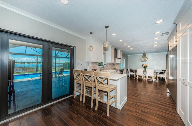 10866 Harborside Dr, Largo, FL 33773 - kitchen with white cabinets, light countertops, dark wood-type flooring, crown molding, and plenty of natural light
