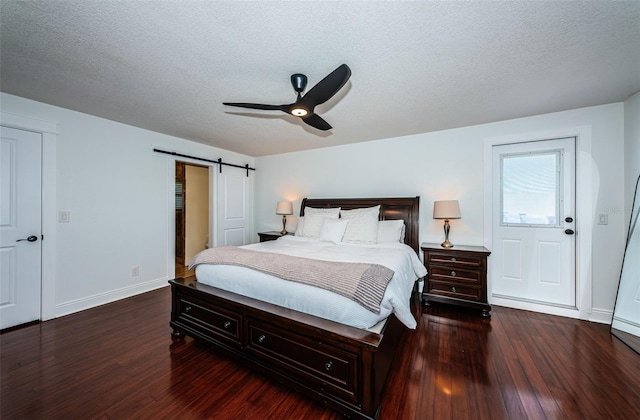 10866 Harborside Dr, Largo, FL 33773 - bedroom featuring dark wood finished floors, a barn door, a textured ceiling, and ceiling fan