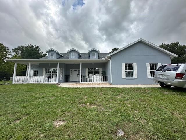 16231 SE 80th St, Morriston, FL 32668 - back of property featuring a porch, a yard, and stucco siding