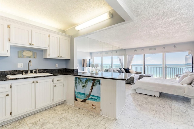 1270 Gulf Blvd Unit 1605, Clearwater Beach, FL 33767 - kitchen with a textured ceiling, open floor plan, a peninsula, white cabinets, and light marble finish flooring