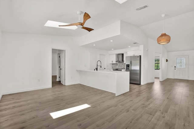 10319 Alberta Ct, New Port Richey, FL 34654 - unfurnished living room featuring a skylight, vaulted ceiling, ceiling fan, and light wood-style flooring