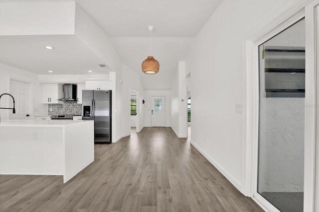 10319 Alberta Ct, New Port Richey, FL 34654 - kitchen featuring stainless steel appliances, wall chimney range hood, white cabinets, light countertops, and light wood finished floors