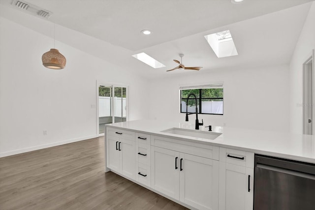 10319 Alberta Ct, New Port Richey, FL 34654 - kitchen with dishwasher, a skylight, white cabinetry, light countertops, and light wood finished floors