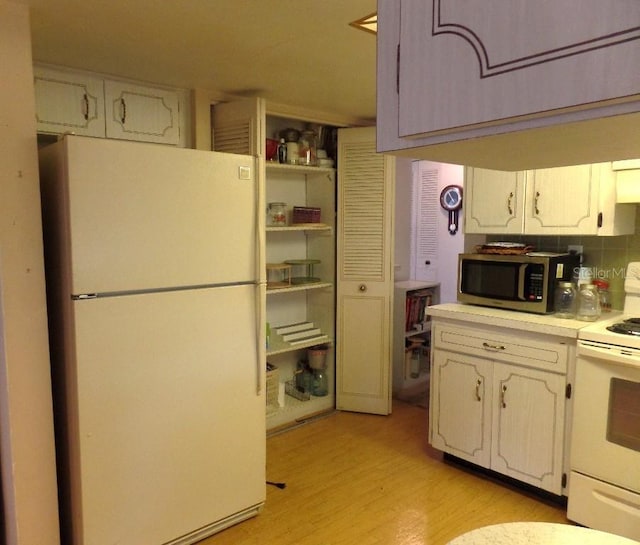 7534 Betula Dr, New Port Richey, FL 34653 - kitchen featuring white appliances, light wood-style flooring, light countertops, decorative backsplash, and white cabinets