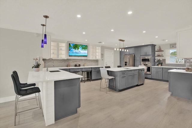 11890 Walker Ave, Seminole, FL 33772 - kitchen featuring appliances with stainless steel finishes, gray cabinetry, a kitchen breakfast bar, decorative backsplash, and open shelves