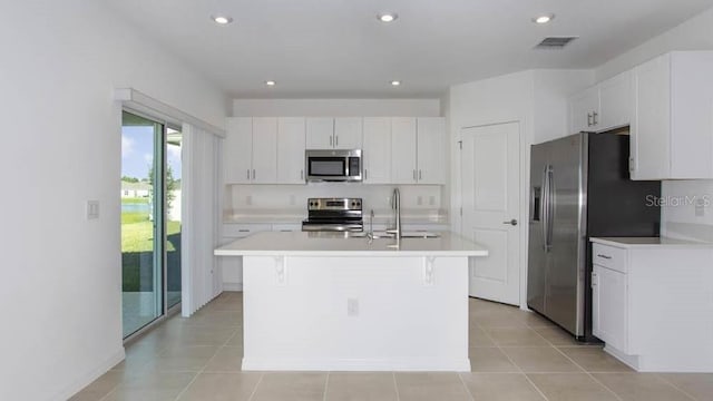 2091 Babbling Brook Blvd, Auburndale, FL 33823 - kitchen with stainless steel appliances, light countertops, white cabinetry, a center island with sink, and light tile patterned flooring
