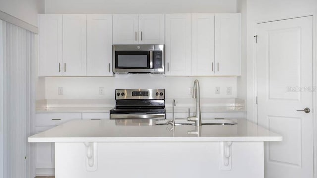 2091 Babbling Brook Blvd, Auburndale, FL 33823 - kitchen with stainless steel appliances, white cabinetry, a breakfast bar area, and light countertops