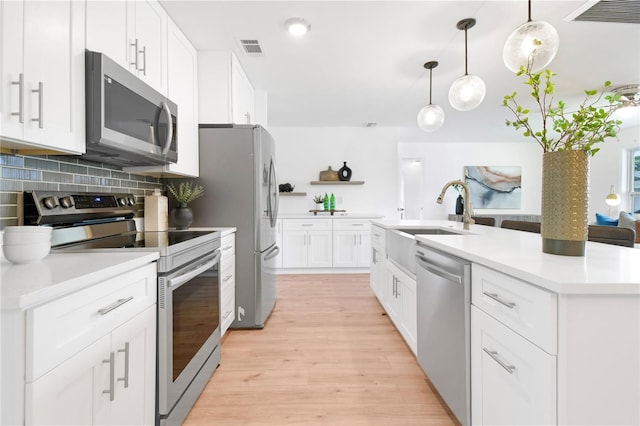 13344 Sorrento Dr, Largo, FL 33774 - kitchen featuring stainless steel appliances, decorative backsplash, open shelves, light countertops, and light wood-style flooring