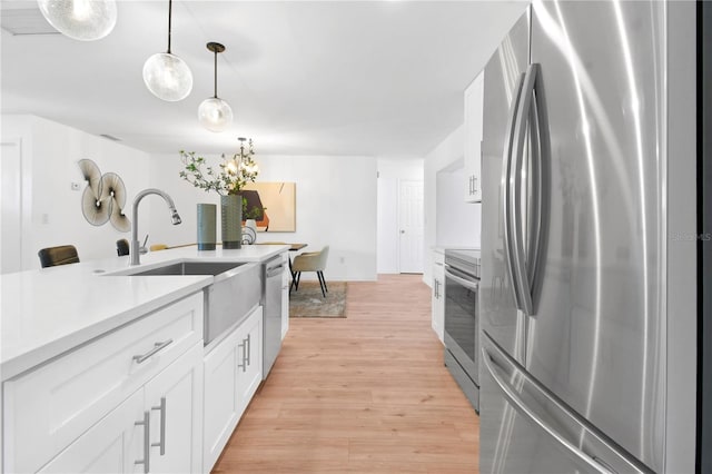 13344 Sorrento Dr, Largo, FL 33774 - kitchen with appliances with stainless steel finishes, white cabinets, light wood-type flooring, pendant lighting, and light countertops