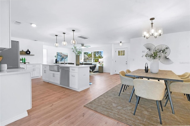 13344 Sorrento Dr, Largo, FL 33774 - kitchen with stainless steel appliances, white cabinets, light wood-style flooring, and light countertops