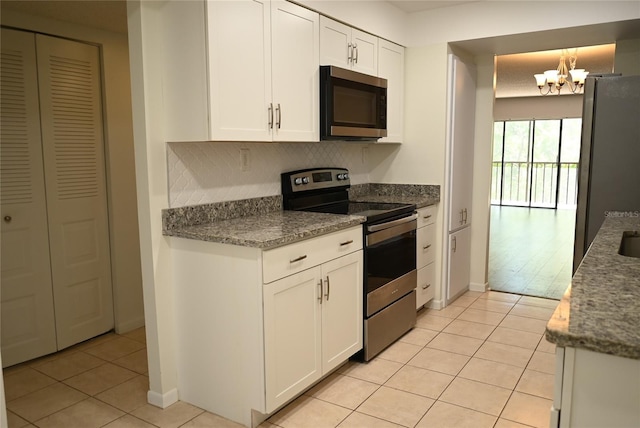 2800 Cove Cay Dr Unit 5D, Clearwater, FL 33760 - kitchen featuring appliances with stainless steel finishes, light tile patterned floors, a chandelier, white cabinetry, and tasteful backsplash